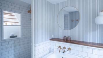 Un baño con un lavamanos blanco, un espejo con marco dorado y una ventana con vigas de madera.