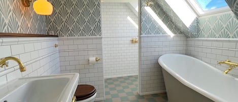 Un bagno con una vasca da bagno bianca, un lavandino bianco, un WC e un lucernario.