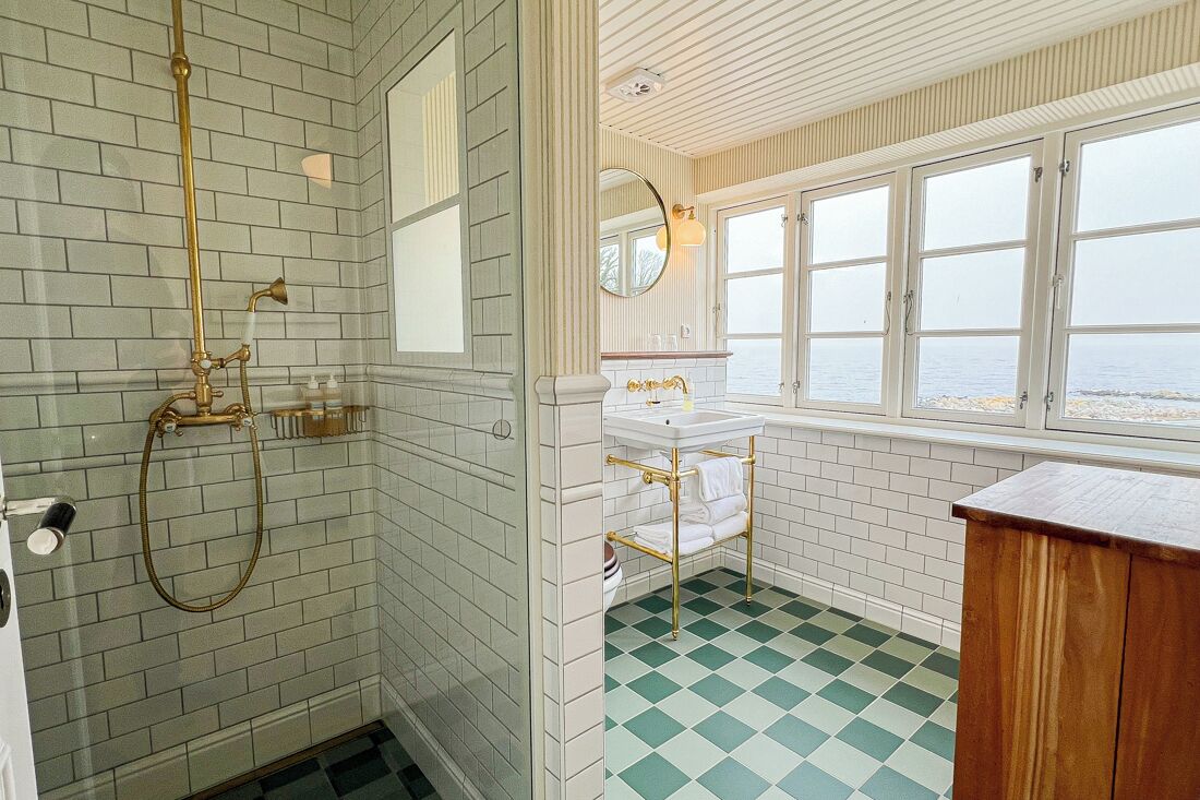 A bathroom with a checkered floor, a window with a view, and a sink with a towel rack.