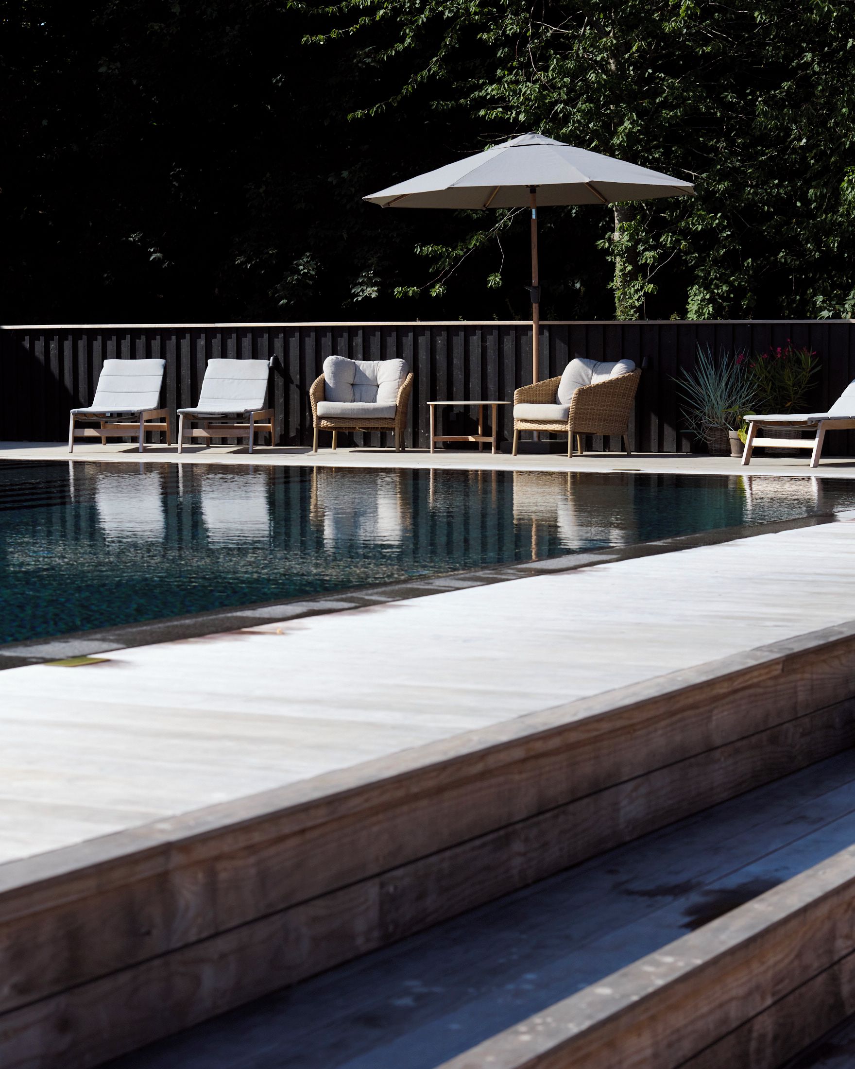 Una piscina con sillas de descanso y una zona con sombra.