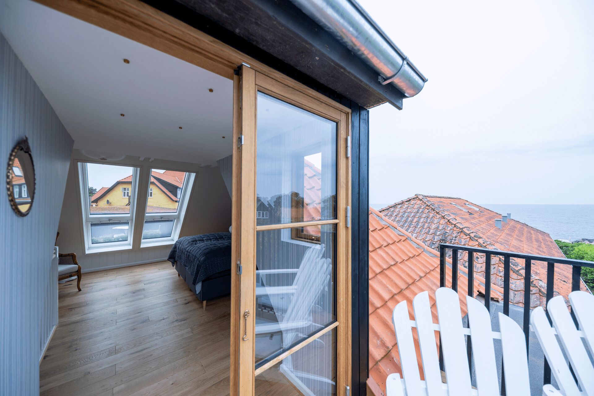 Una habitación con un gran ventanal corredera que da a un balcón con vistas al mar.