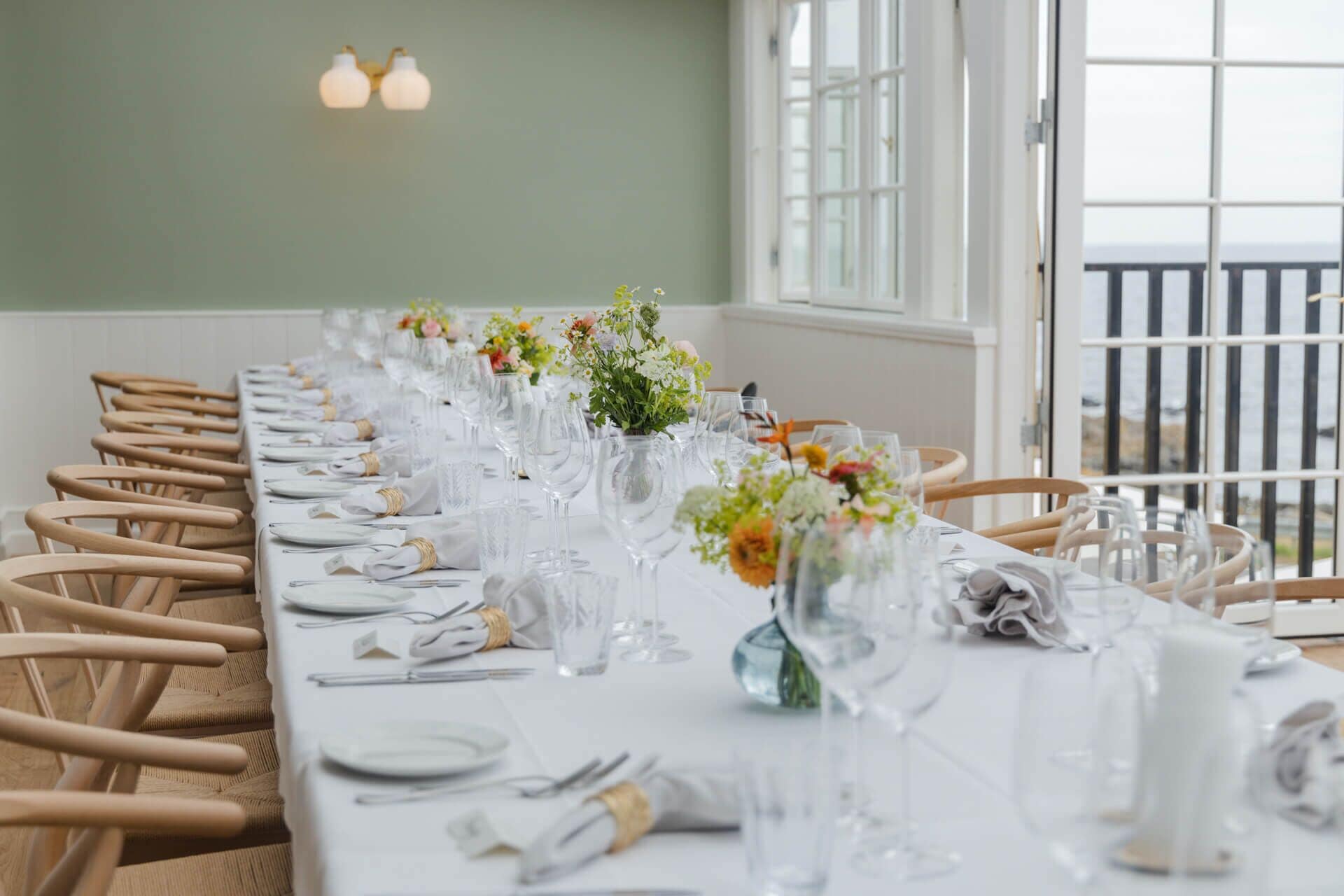 A long dining table set with white tablecloths, glassware, and floral centerpieces.