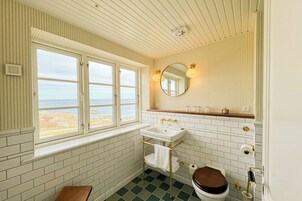 Et badeværelse med vindue, vask, toilet og spejl.