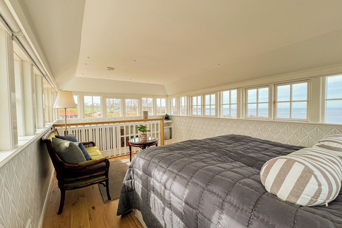 Un dormitorio con una cama grande, un rincón con asiento junto a la ventana y una vista al exterior.