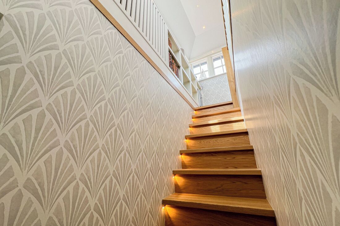 A wooden staircase with a geometric patterned wall on either side.