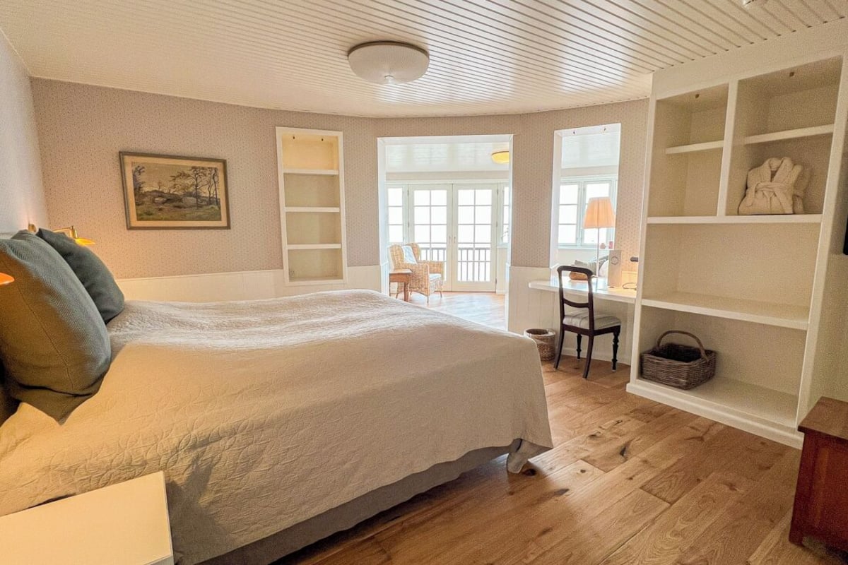 A bedroom with a large bed, a desk, and built-in shelving.