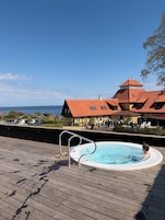 En træterrasse med jacuzzi, swimmingpool og en bygning med rødt tag og gule vægge.