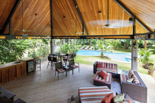A covered outdoor area with a pool, seating, and a kitchen area. - CASA PUMILIO: Family Vacation Home w/concierge service! Mountain, 5min to Beach. (Pueblo Nuevo, Garabito)