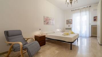 A bedroom with a bed, a chair, a nightstand, a lamp, and a painting on the wall.