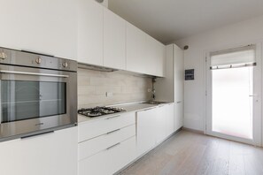 A modern kitchen with white cabinets, a stainless steel oven, and a gas stove.
