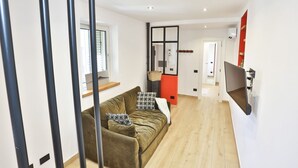Ein modernes Wohnzimmer mit einer Couch, einem Fernseher und Holzböden.