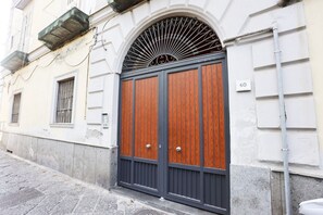A building with a large wooden double door, a metal arch above the door, and a number '60' on the wall.
