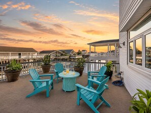 A rooftop patio with outdoor seating, potted plants, and a view of the waterfront.