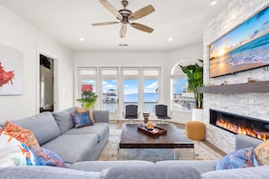 A living room with a gray sofa, a coffee table, a fireplace, and a television.