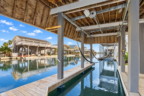A pool area with wooden deck, a covered seating area, and a view of a resort building.