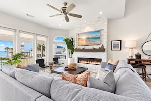 A spacious living room with a fireplace, large windows, and a view of the ocean.