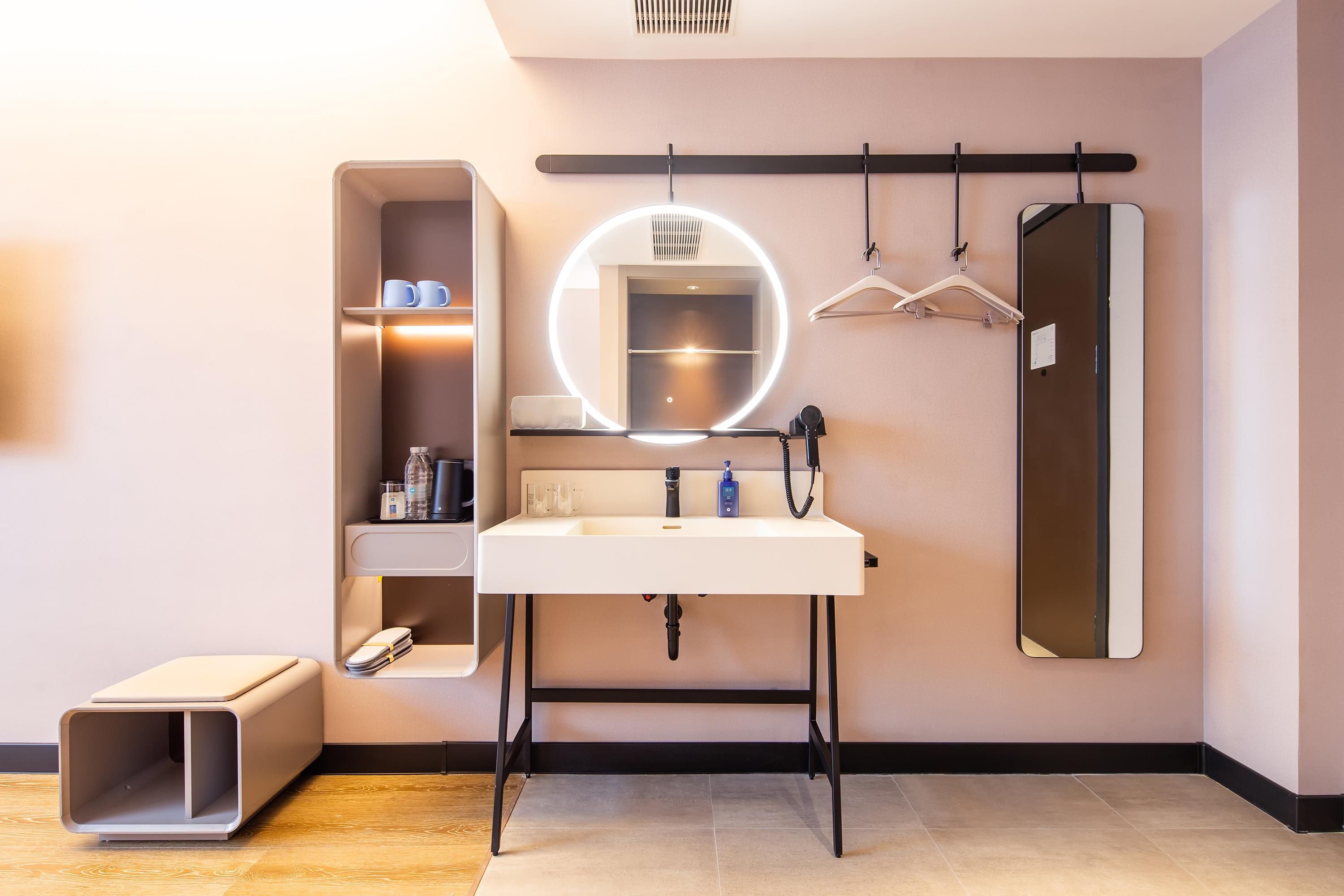 A modern bathroom with a vanity, mirror, and hanging clothes rack.