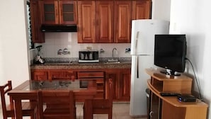 Eine kleine Küche mit Holzausstattung, einer Mikrowelle, einem Kühlschrank und einem Fernseher auf einem Holzständer.