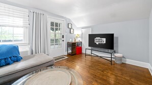 Una sala de estar con televisor, sofá, mesa de centro y ventana con cortinas.