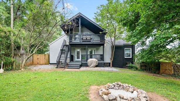 A two-story house with a front porch, a covered staircase, and a fire pit in the yard. - Memories on Madison | Entire Home w/ Game Room & Outdoor Fire Pit (102 Madison Ter) (Clarksville)
