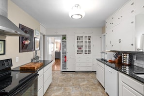A kitchen with white cabinets, a black stove, and a tiled floor.