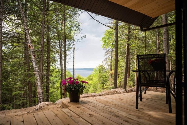 A wooden deck with a view of a forest and a body of water.