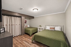 Un dormitorio con dos camas individuales, un armario de madera, una mesita de noche y una lámpara en el techo.