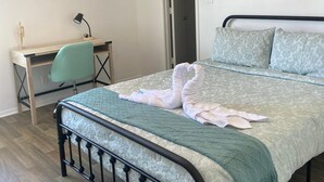 Ein Schlafzimmer mit einem Bett, einem Schreibtisch und einem Deckenventilator.