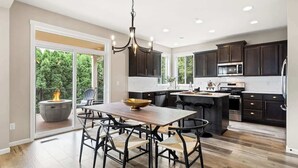 A spacious kitchen with dark cabinets, a central island, and a dining area with chairs. - 5 Bedroom Home w/Guest Suite & Private Sauna (Camas)