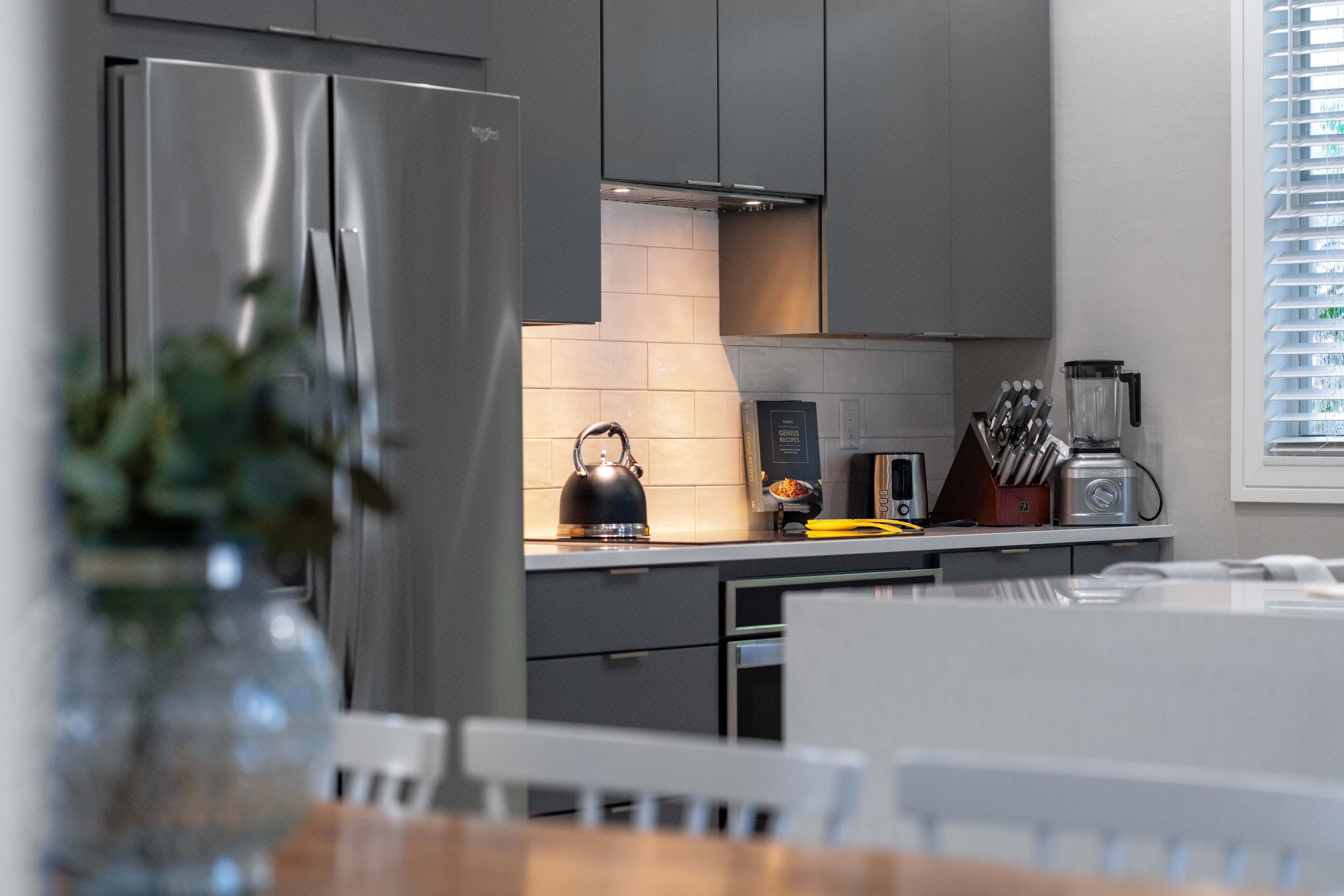 A modern kitchen with stainless steel appliances, a kettle, and a knife block.