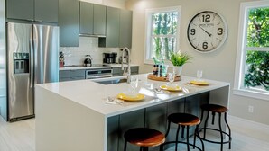 Eine moderne Küche mit Kochinsel, Edelstahlgeräten und einer großen Wanduhr.