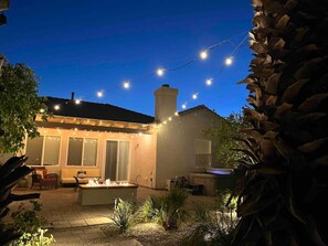 A patio area with string lights, a fire pit, and outdoor furniture.