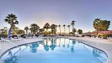 A swimming pool with lounge chairs and palm trees.