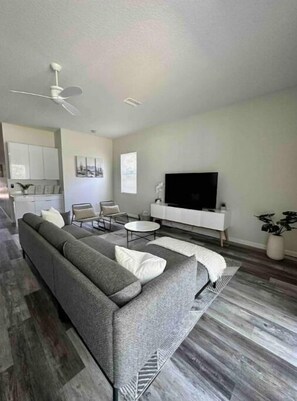 Relax in this stylish living room with a large sofa, flat-screen TV, and potted plant.