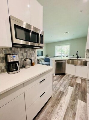 Kitchen features a stainless steel microwave, coffee maker, and white cabinet with a drawer.