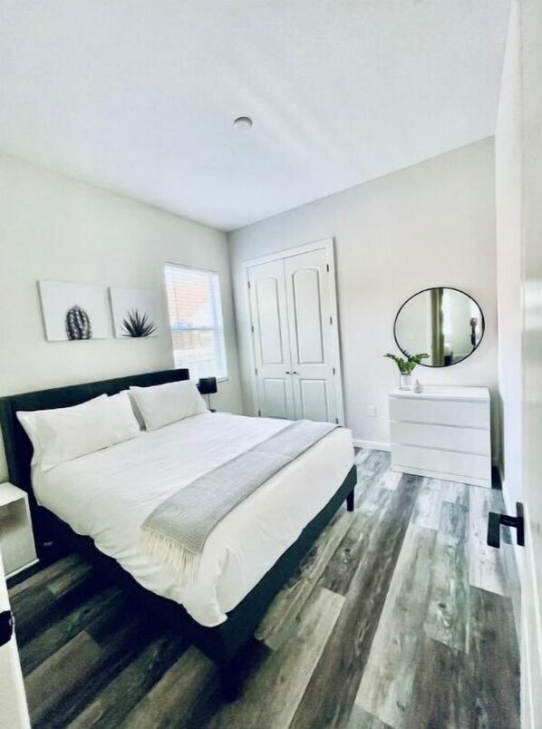 Relax in a serene bedroom with a large bed, dresser, and window with blinds.