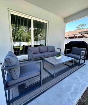 Relax in an outdoor space with a sofa, armchairs, and a table, perfect for al fresco dining and cooking.