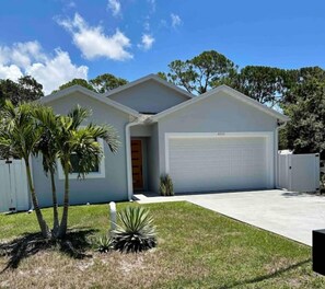 Enjoy a single-story home with a garage, beautifully set amidst a well-maintained lawn and palm trees.