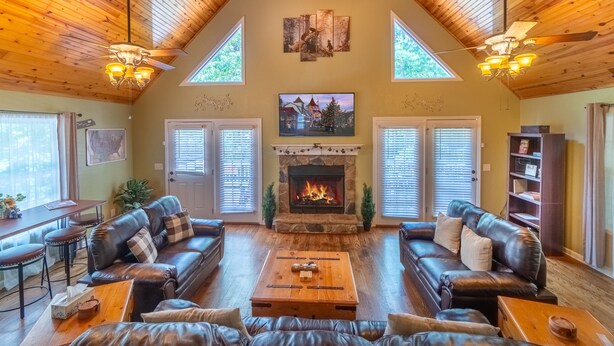 Una sala de estar acogedora con chimenea, sofás de cuero y techo de madera.