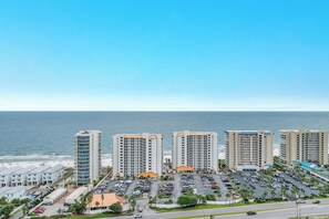 A coastal hotel with multiple high-rise buildings, a parking lot, and a beach view. - POOL, BEACH FRONT, PRIVATE BALCONY! (Orange Beach)