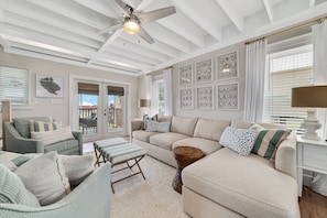 A spacious living room with a high ceiling, a ceiling fan, and a large window with blinds. There are multiple seating areas including a sofa, a chair, and a bench. - PET FRIENDLY, NEAR BEACH ACCESS, PRIVATE HOME! (Gulf Shores)