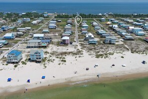 Vue aérienne d’une zone résidentielle côtière, avec des maisons, une plage et une vue dégagée sur l’océan.