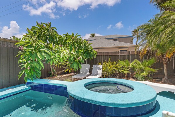 Un jardin avec une piscine, un jacuzzi et une clôture en bois.