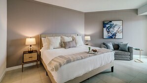 A modern hotel room with a large bed, bedside tables, a sofa, and a painting on the wall. - Direct Bayview One Bedroom Condo in Coconut Grove-includes parking (Coconut Grove)