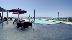 A rooftop pool area with seating and umbrellas, overlooking a cityscape. - Direct Bayview One Bedroom Condo in Coconut Grove-includes parking (Coconut Grove)