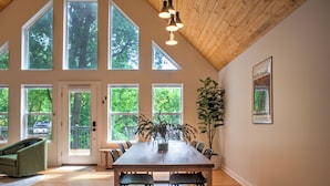 Un comedor amplio con una gran mesa de madera, varias sillas y una planta en maceta.