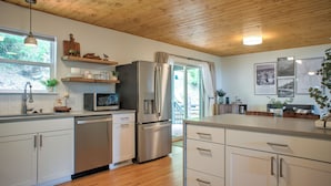 Una cocina moderna con techo de madera, electrodomésticos de acero inoxidable y vistas al exterior.