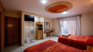 A hotel room with two beds, a TV, a desk, and a wardrobe.