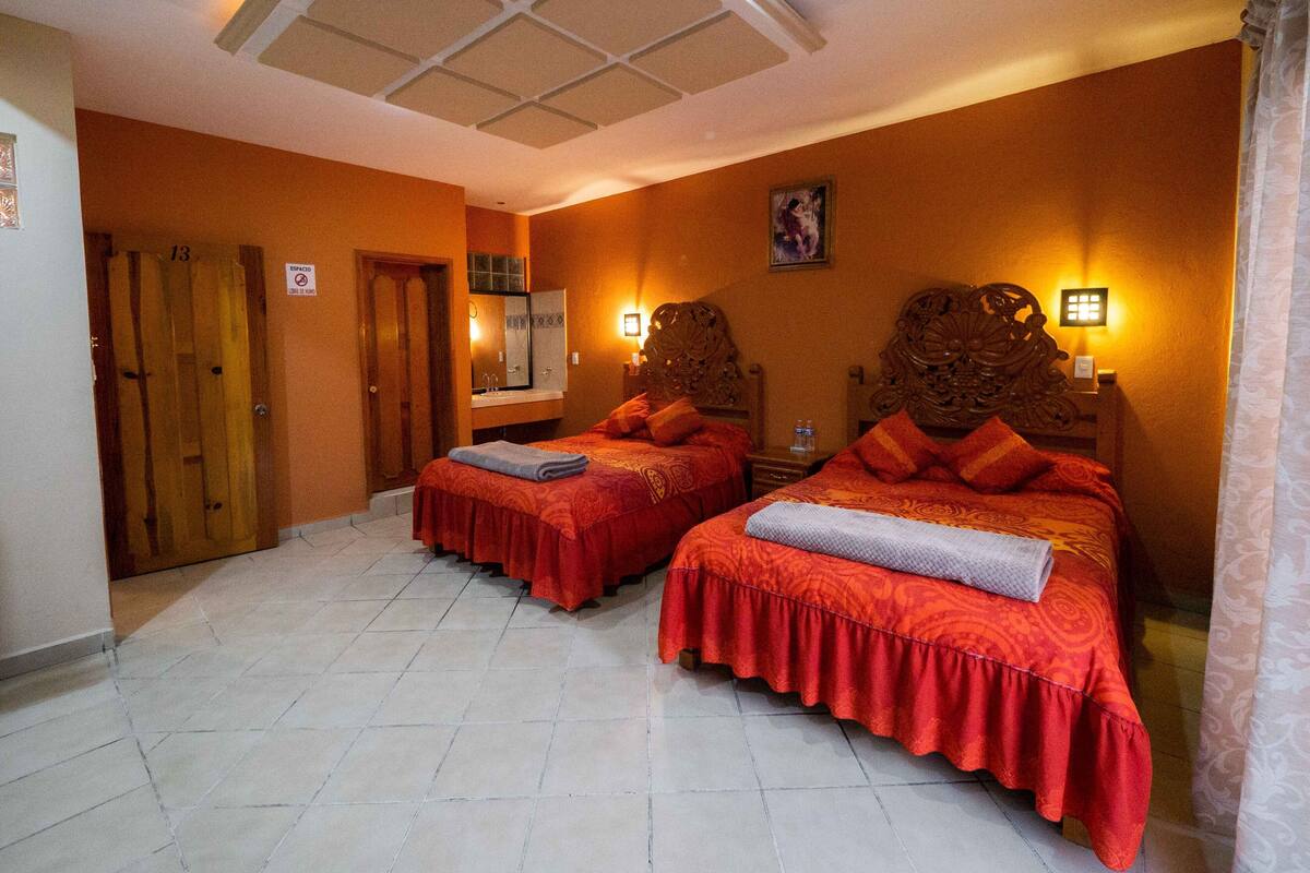 A hotel room with two beds, a bathroom, and a door marked with the number 13.