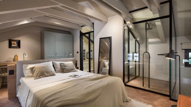Un dormitorio con cama, escritorio, armario y cabina de ducha de vidrio.